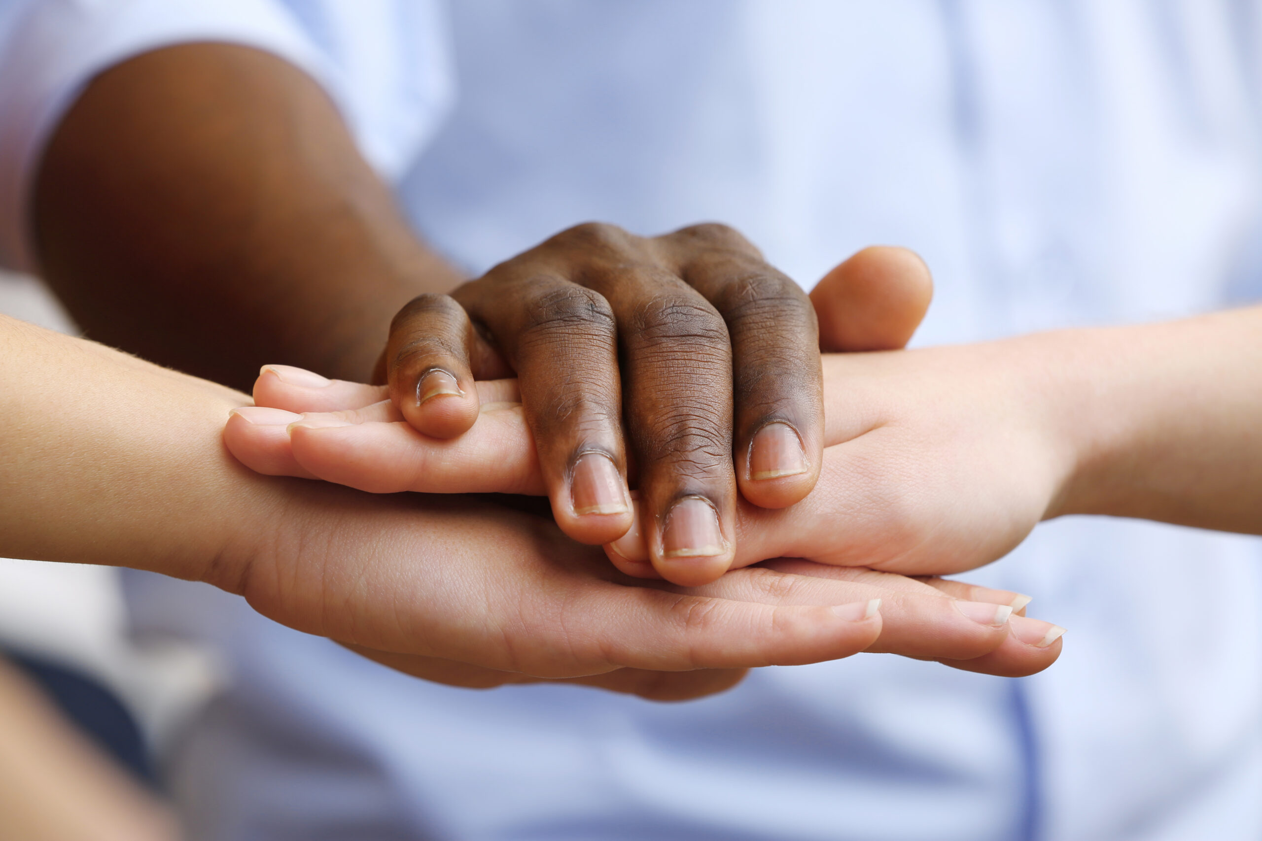 White caucasian and black afro american hands holding together